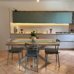 Cucina moderna su misura con pensili verde salvia e tavolo in legno realizzata da 2ZC Arredamenti